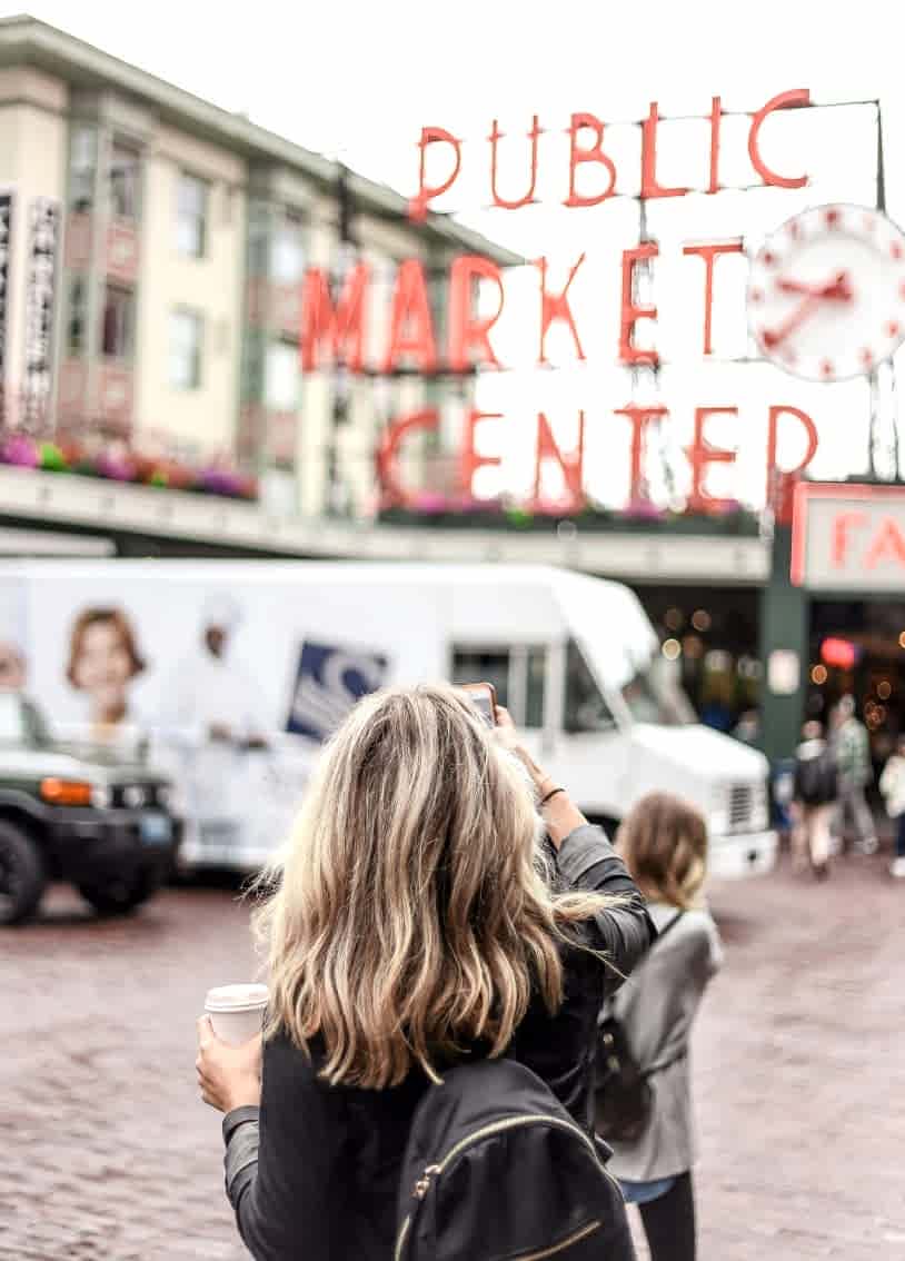 A woman capturing a photo of a sign with her smartphone.