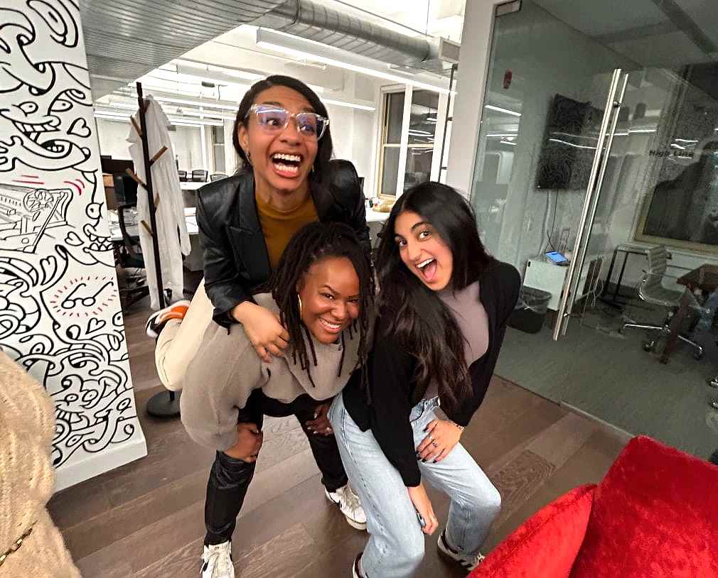 Three women smiling and posing for a photo in an office setting.