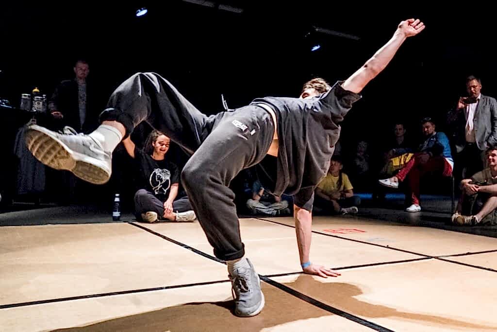 Man breakdancing in front of a darkened crowd