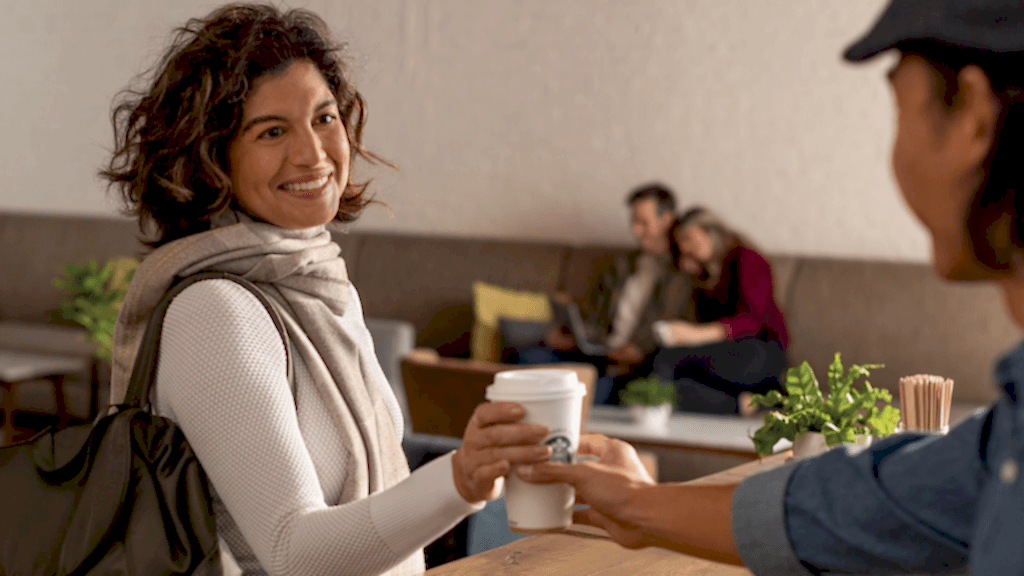 Woman smiling while being handed a cup of Starbucks coffee