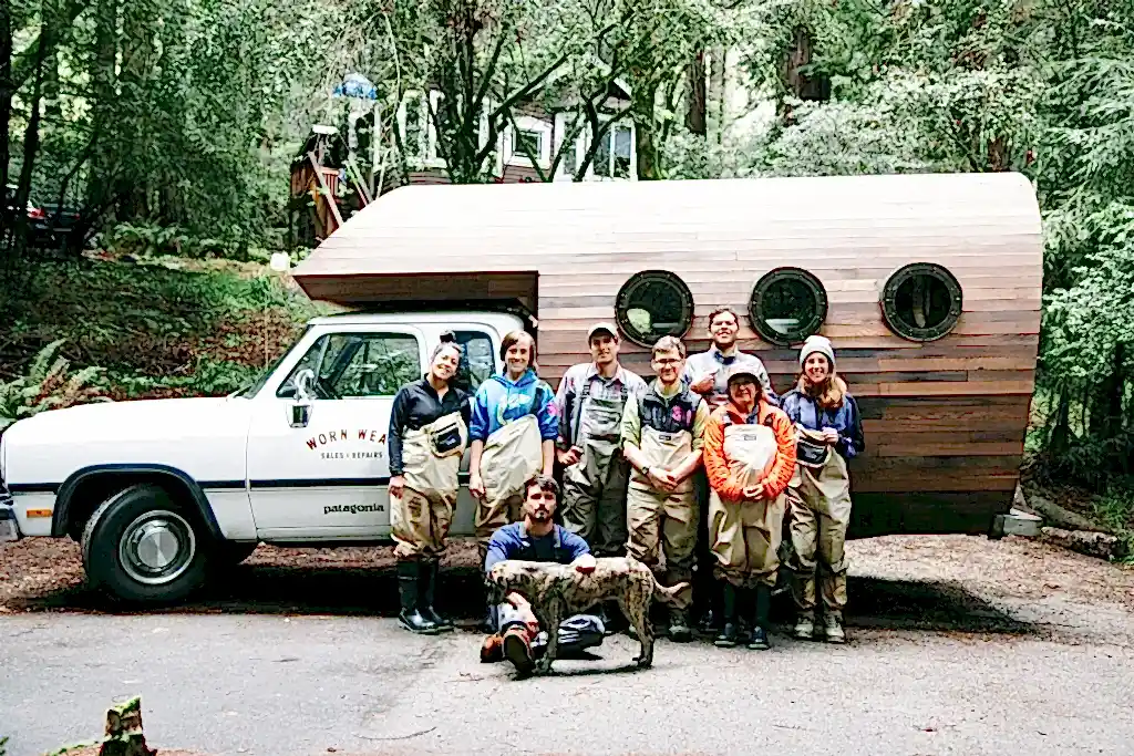 Team of people in outdoor workwear smiling in front of a Worn Wear Patagonia truck