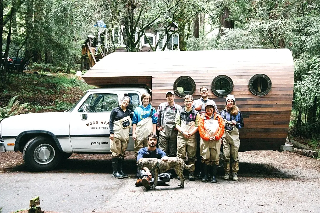 Team of people in outdoor workwear smiling in front of a Worn Wear Patagonia truck