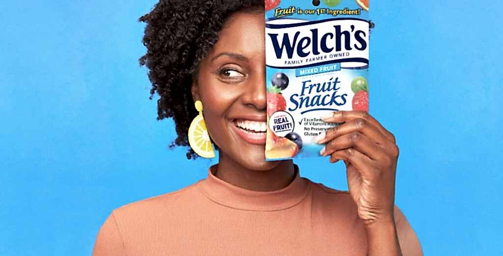 Woman smiling while holding a bag of Welch's fruit snacks in front of her face