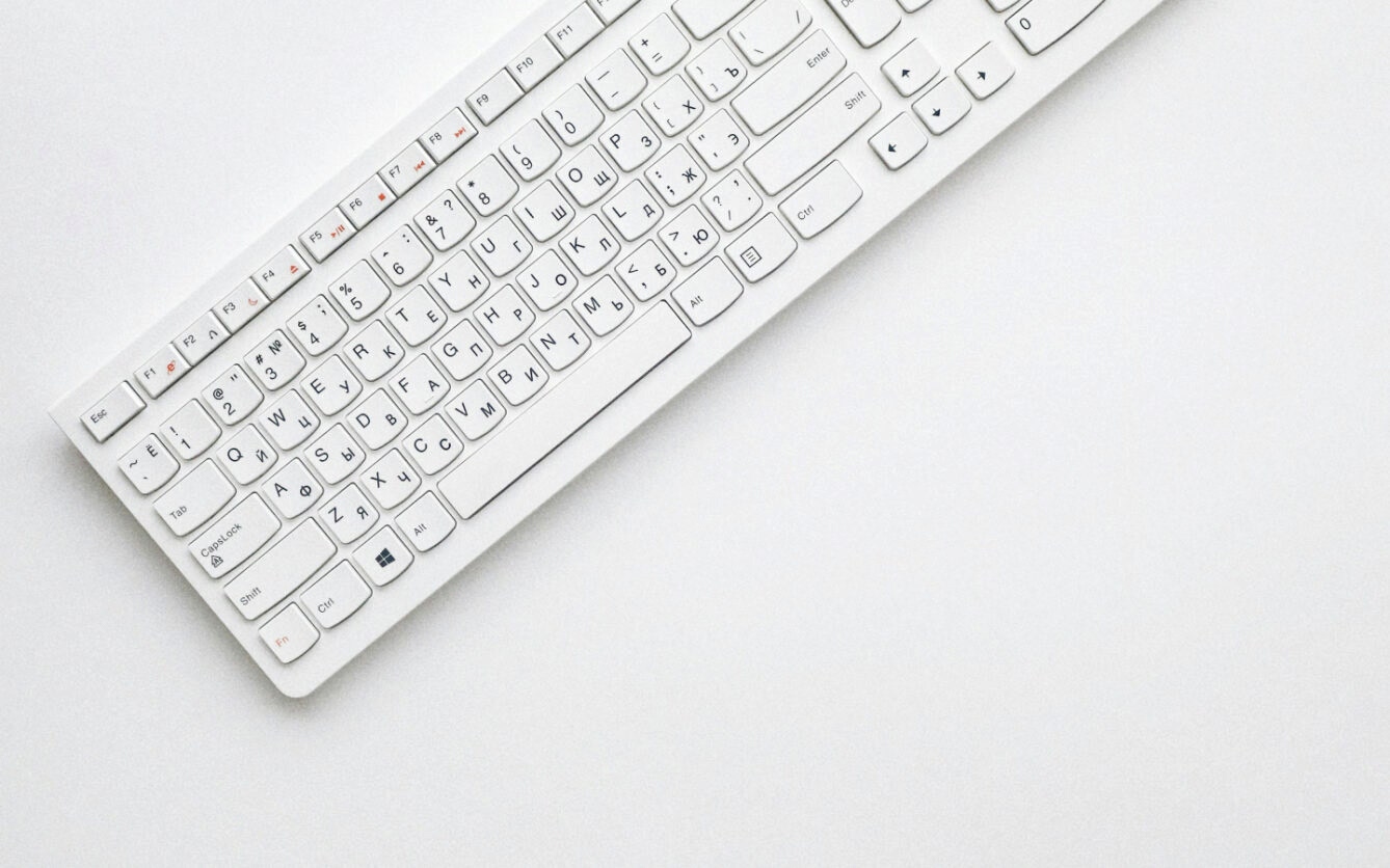 White keyboard with Russian and English letters on the keys, positioned diagonally on a plain white surface.