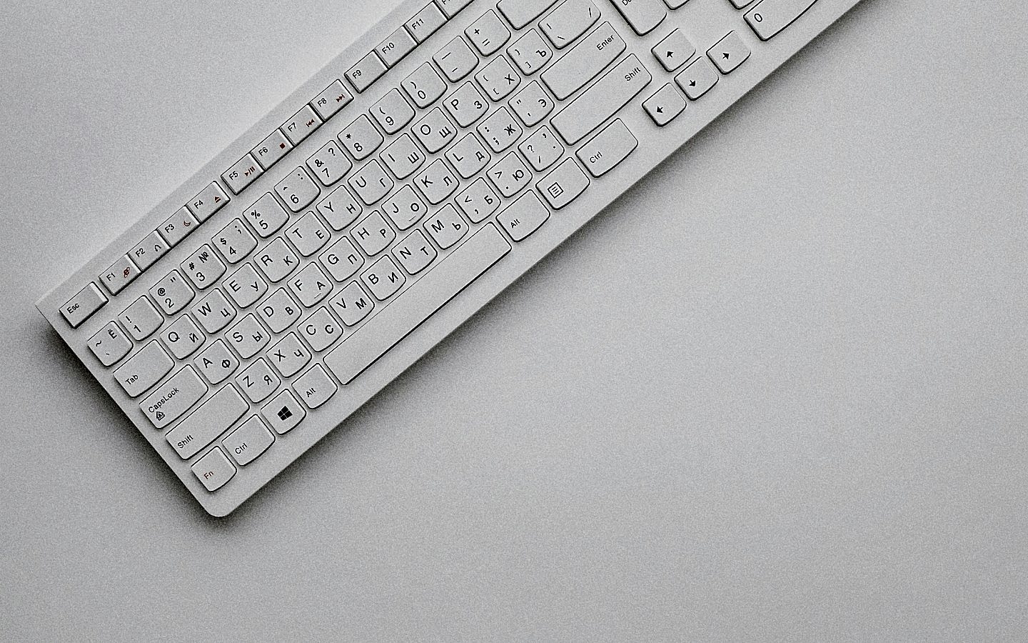 White keyboard with Russian and English letters on the keys, positioned diagonally on a plain white surface.